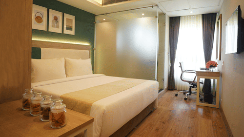 view of the double bed, side table, television, and the work desk and chair in one of the standard rooms at Sarovar Portico, Kolkata Rajarhat