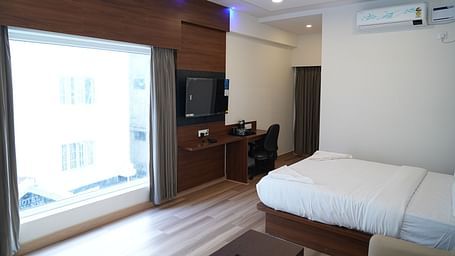 a huge window allowing plenty of natural light to enter the room highlighting the double bed and the coffee table beside it - Hotel Grand Sigma
