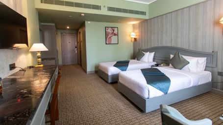 A well-appointed guest room at Shilton International, Kochi, with two beds and a desk area.