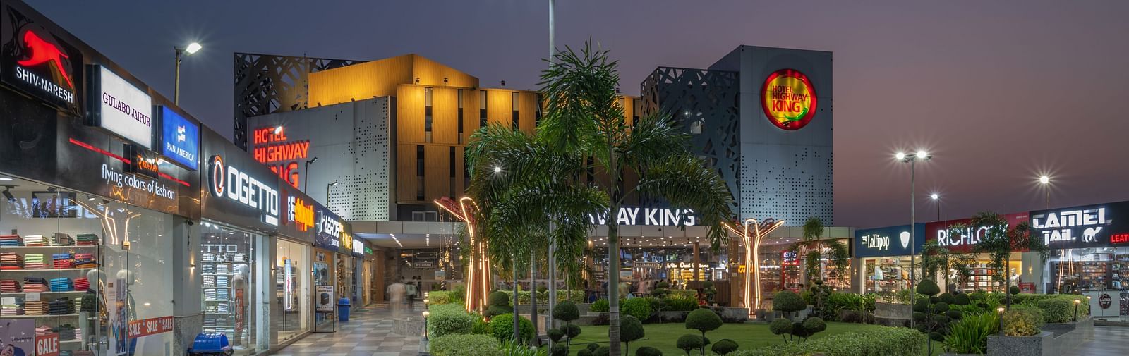 Retail and garden area near the hotel entrance with evening lights at Hotel Highway King, Bilaspur.