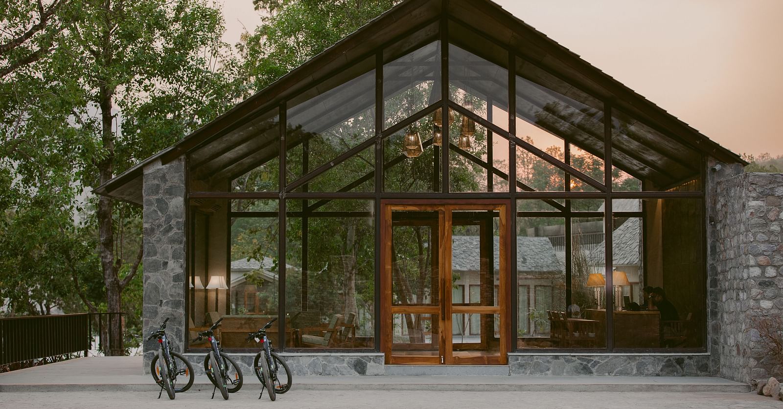 Entrance to Saraca Resort & Spa Corbett with large glass panels and wooden beams