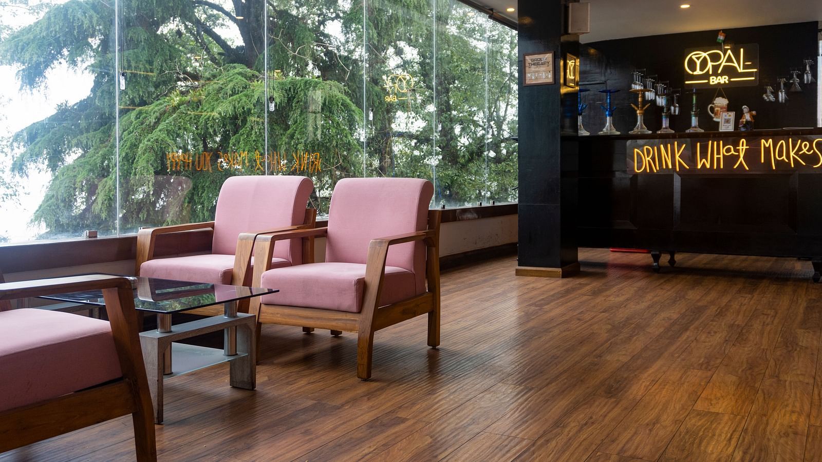A wide shot of a bar at Orsino Spa Resort with large windows offering a view of pine trees.