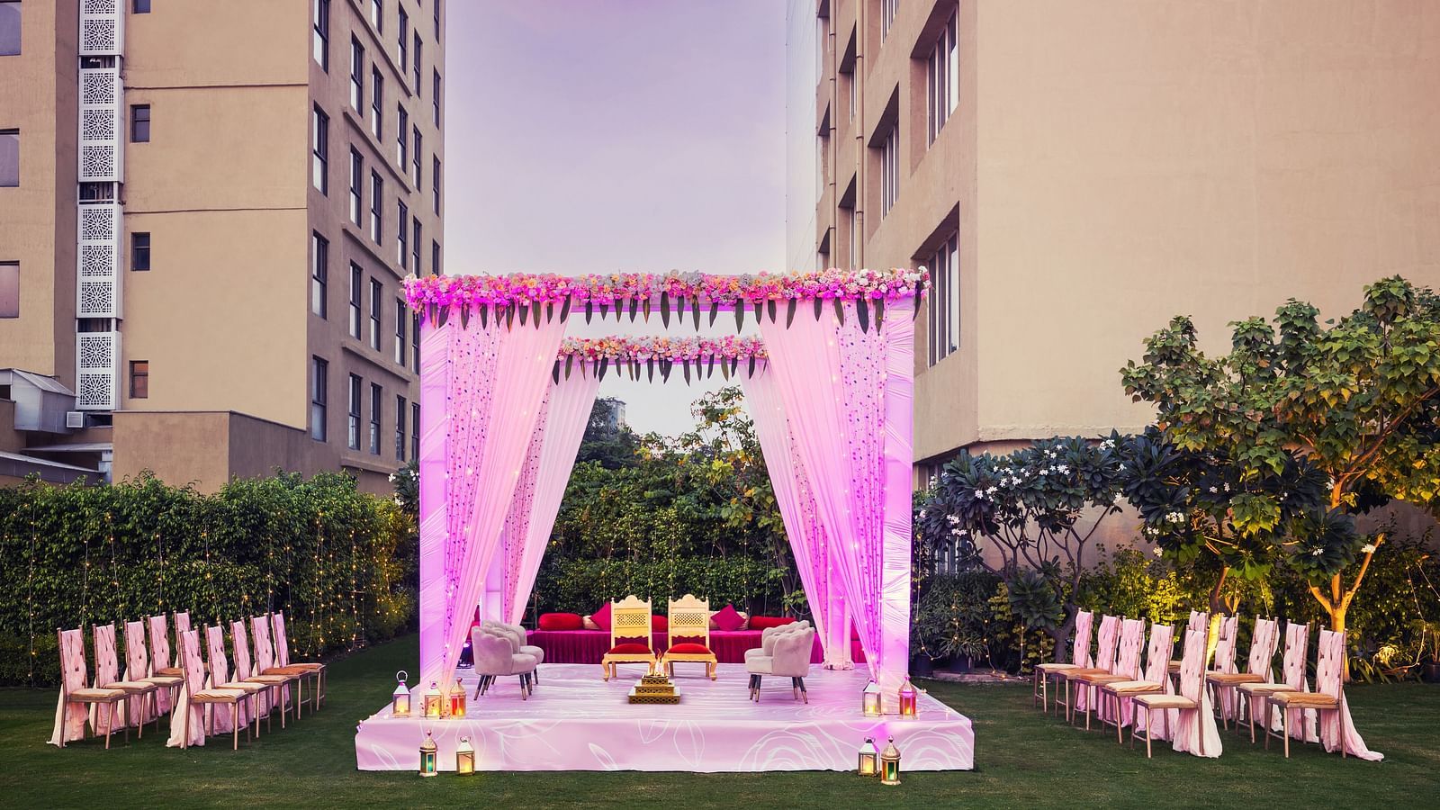 a stage set with two chairs and a canopy above and a group of chairs lined up on either side of the stage - The Hideaway Banquets & Lawns, Greater Noida