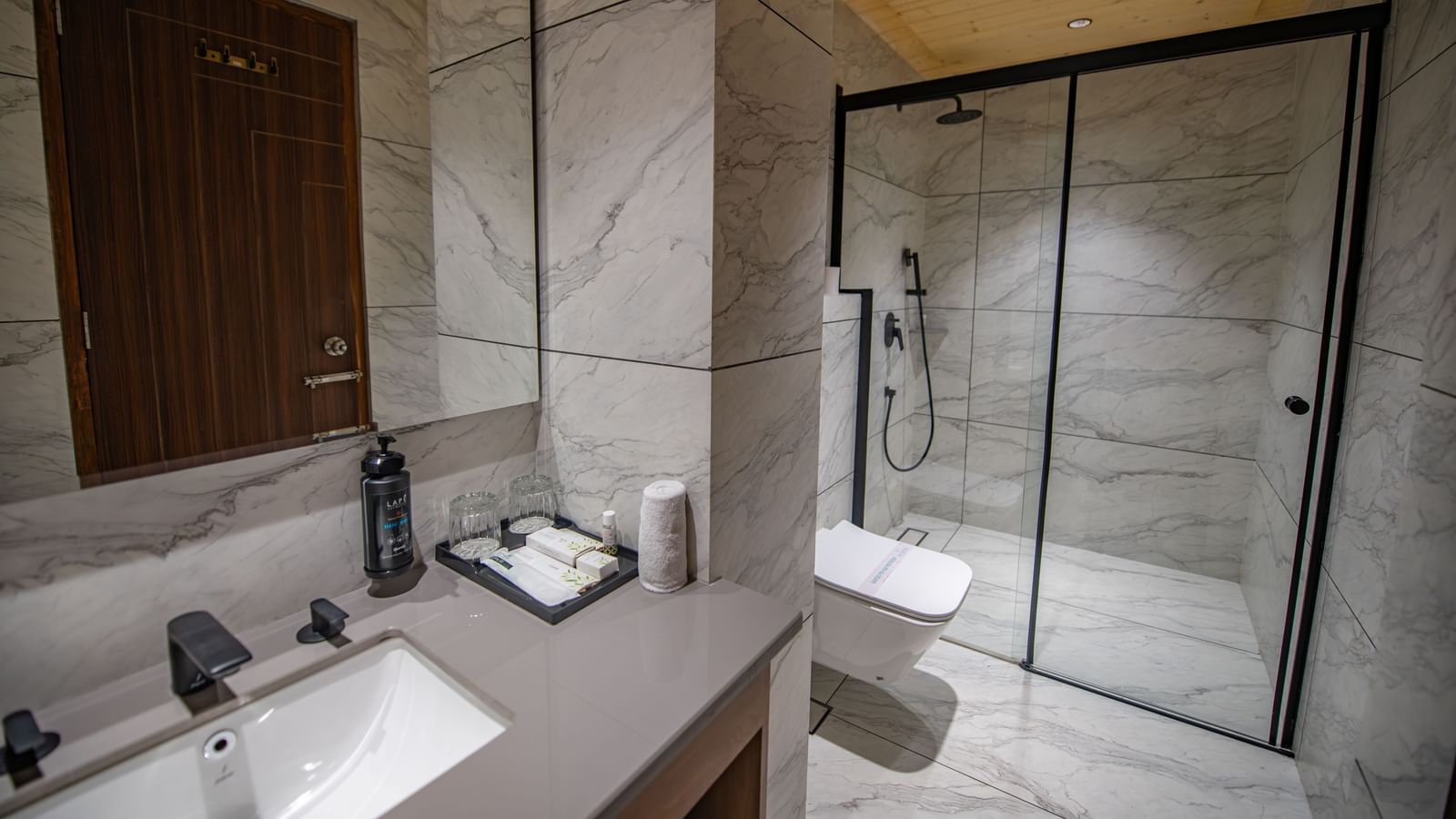  A bathroom in the deluxe room at The Tattva Devaprayag with a toilet, a sink, and a glass shower cubicle.