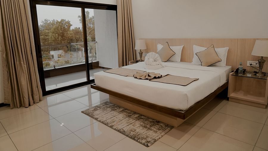 Pride Ranakpur Resort Convention Centre - interior view of the super deluxe room containing a king size bed and cream coloured decor