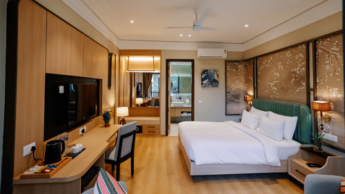 Pride Premier Alwar | A room with a large bed, bedspreads, pillows, a television, and mirrors