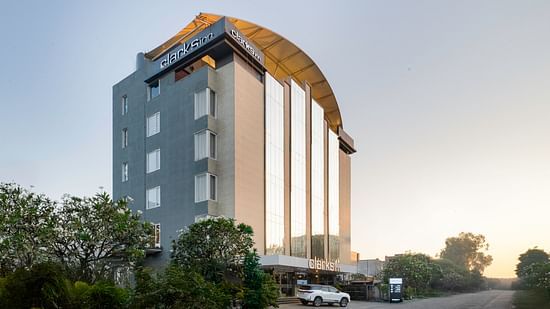 Exterior view of a Clarks Inn hotel, showcasing its modern architecture and surrounding landscape.