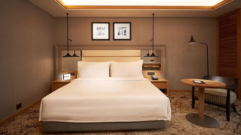 a room image with a bed, table, chair all arranged and  false ceiling lights giving a warm ambience