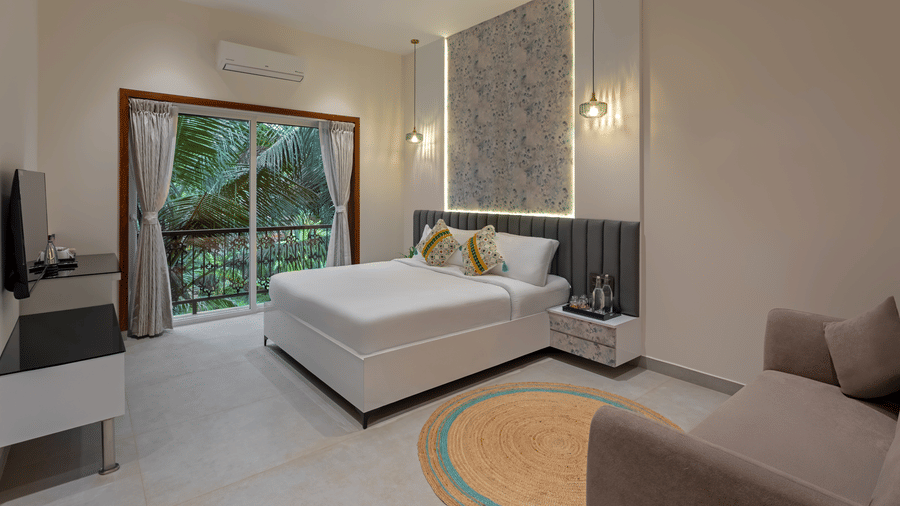 Deluxe room with king bed and large glass doors opening to a garden view at Lamrin Morjim Goa.