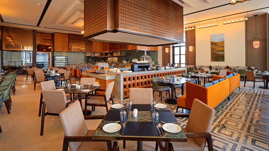 Dining area with an open kitchen counter and warm wood accents at Chithirai restaurant, The Residency Signature Madurai, offering a relaxed setting