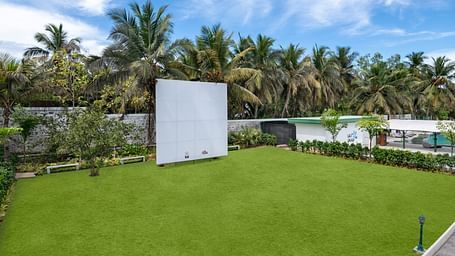 Green outdoor lawn with palm trees and a large white backdrop for events at GRT Hotel.