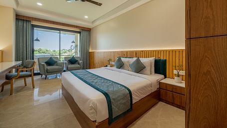 An executive king room with lounge chairs and natural light near the window at Hotel Highway King, Bagru.
