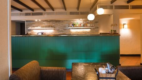 A cosy bar at Shilton International, Kochi, with a well-stocked counter and comfortable seating, ideal for relaxation.