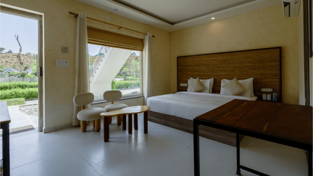 Boho Deluxe with Connected Pool bedroom featuring a bed, seating area, wooden table and a large window with a view at Valley by Grassfield.