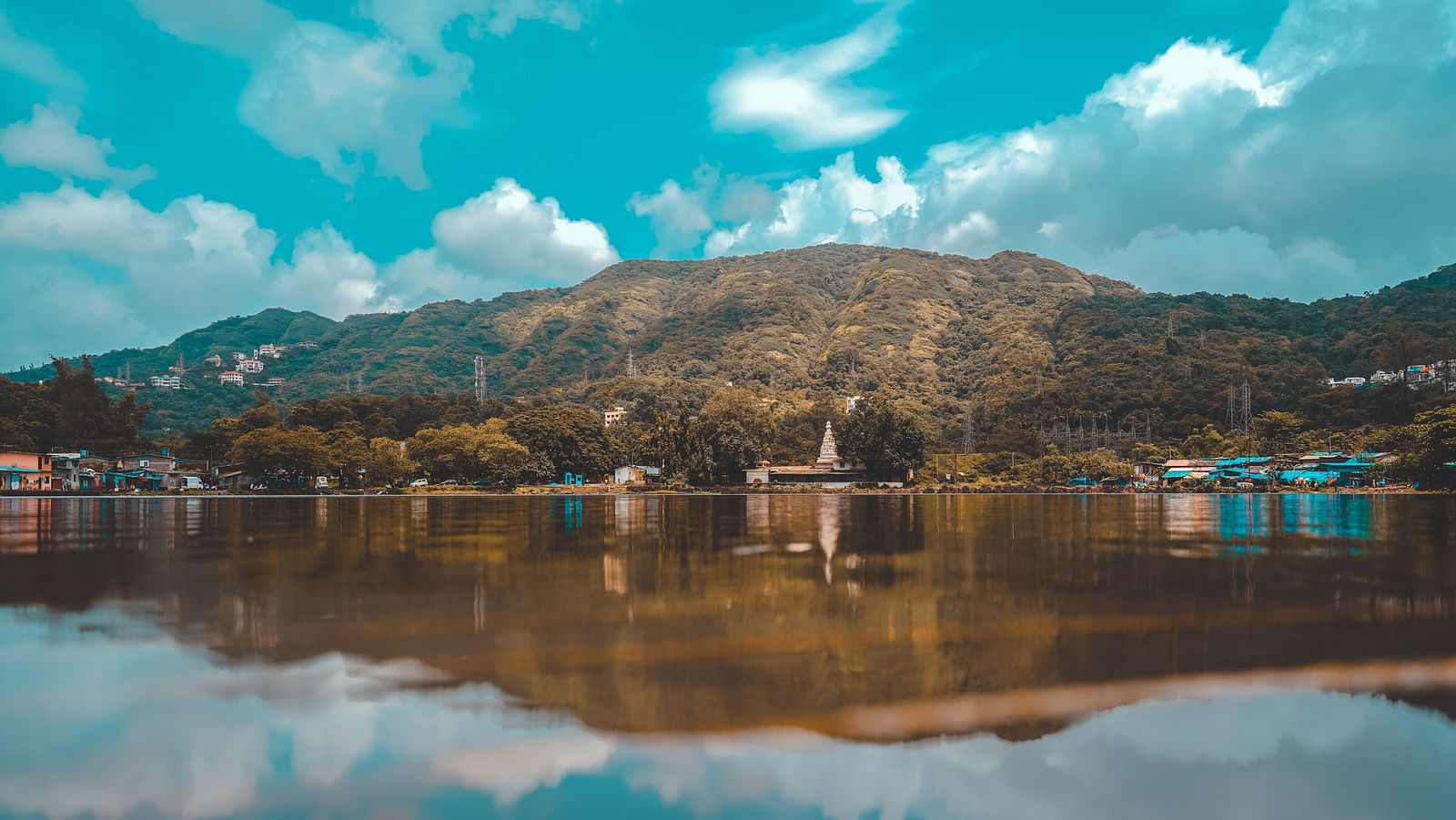 Landscape view of hills with a lake in front and the reflection of the sky on it