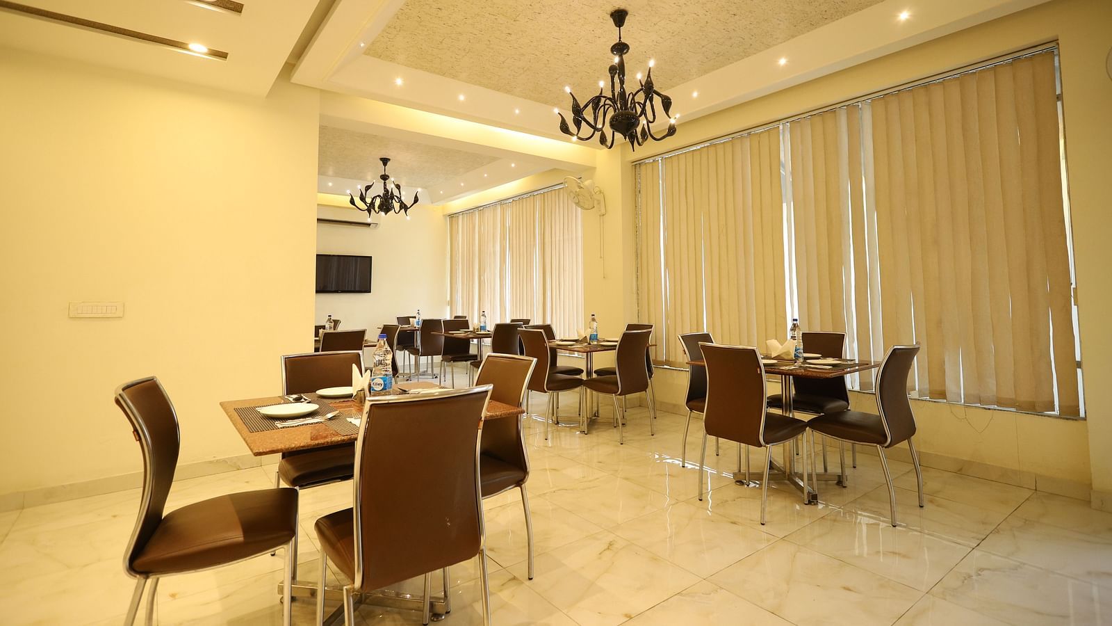 A brightly lit dining area features multiple tables and chairs - Asian Suites Cyber Park, Gurgaon