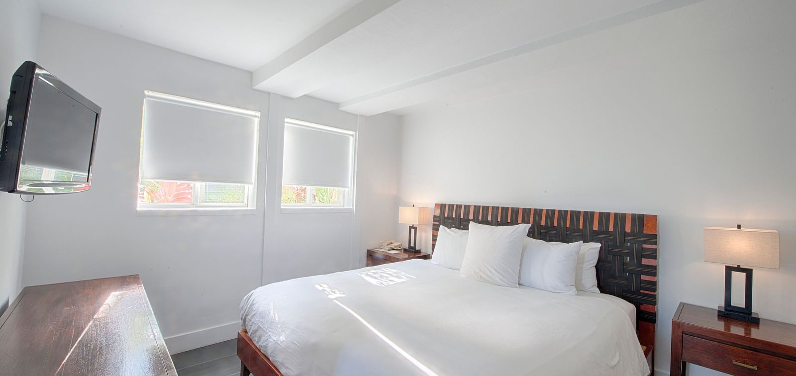 Bedroom at Casa Morada featuring a white bed, wooden furniture, and a wall-mounted TV.