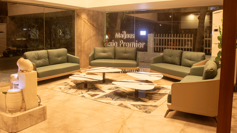 The lobby area with 4 sofas, 4 center table, marble sculpture, and glass entrance at Magnus Lxia Premier, Kalyani Nagar.