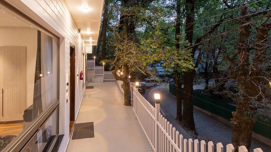 The common balcony area near the rooms at DLS The Emerald, Nainital surrounded by trees and greenery