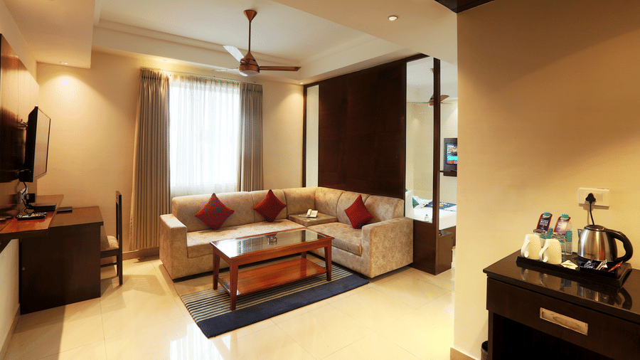 Spacious hotel suite living area with a plush sofa, coffee table, and flat-screen TV - Eastlynn Resort, Rishikesh