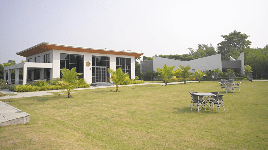 Wide lawn view featuring buildings, outdoor seating, and open green spaces at Hotel Sonar Bangla, Mayapur.