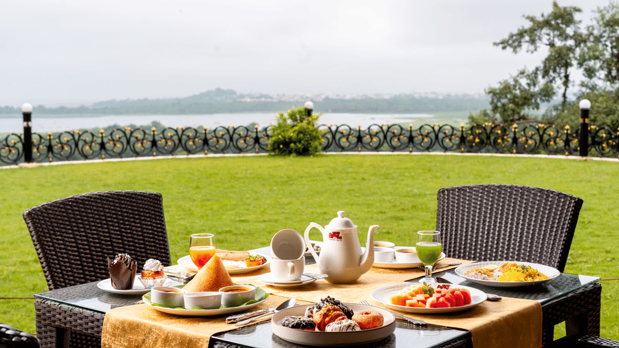 A close up of a dining table with a glass top at the outdoor dining area of the Marble Arch restaurant overlooking the a wide green lawn at Noor-Us-Sabah Palace, Bhopal.