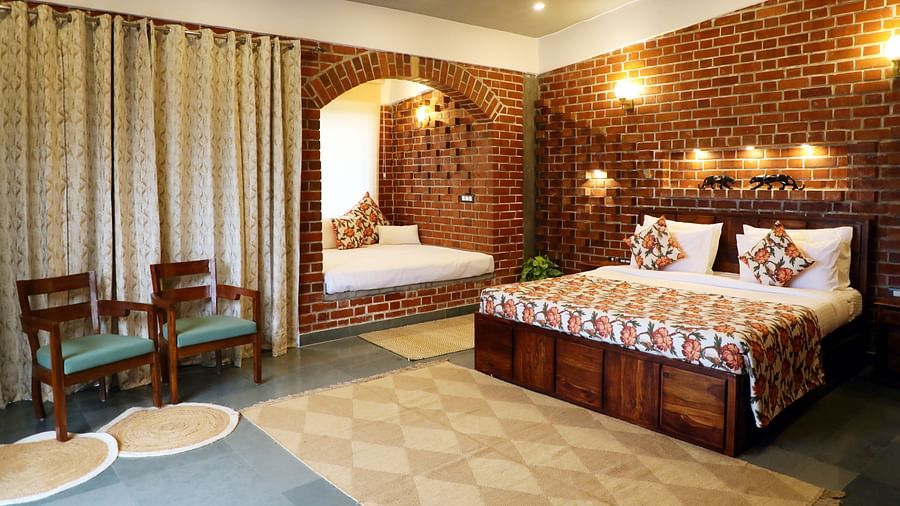 A suite featuring a king size bed with warm lighting illuminating above the bed at Tisya Farms, Gurgaon.