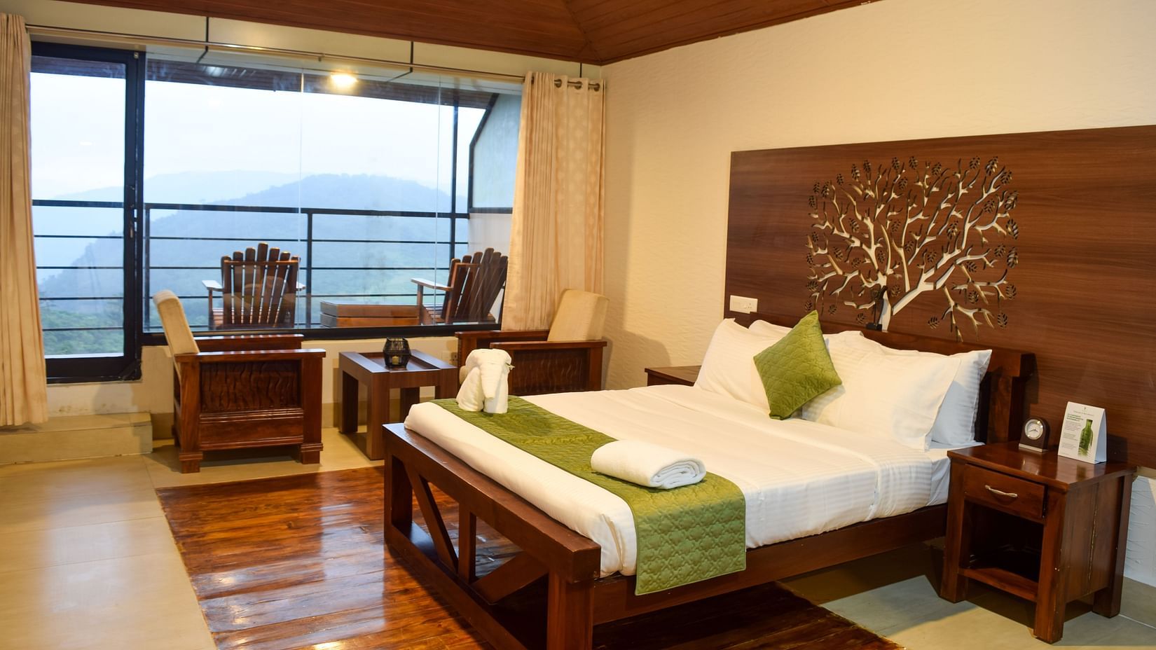 Shot of the suite at the resort featuring a wodden framed king size bed, a private balcony overlooking the mountains | Ibex Stays and Trails