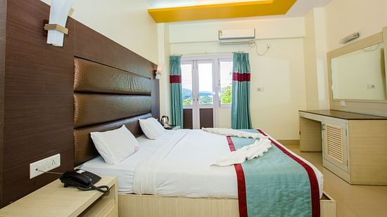 A double bed with side tables, a cushioned headboard and mirror opposite in Sea View - Hotel Shompen