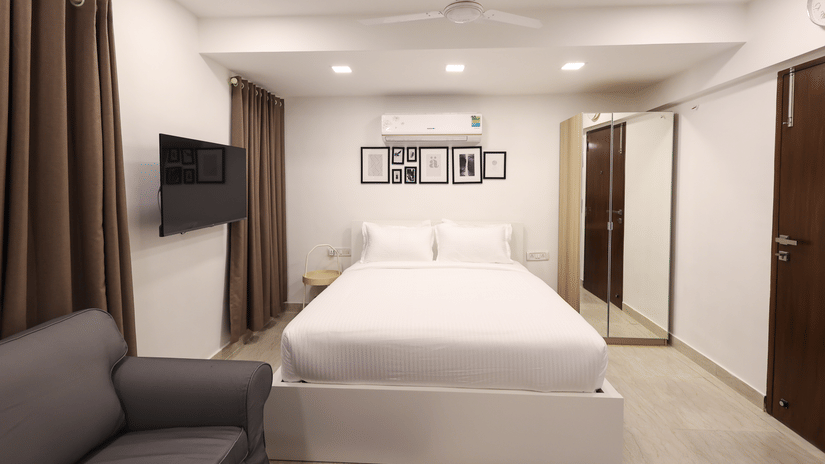 A spacious room with a large bed, seating area, wardrobe and a ceiling fan at Wabi - Sabi by Alamiko, Juhu.