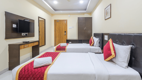 Comfort room with 2 cosy beds, mirror, ceiling fan, wardrobe, and wall-mounted TV at Lemonridge by Monday Hotels - Kukatpally.
