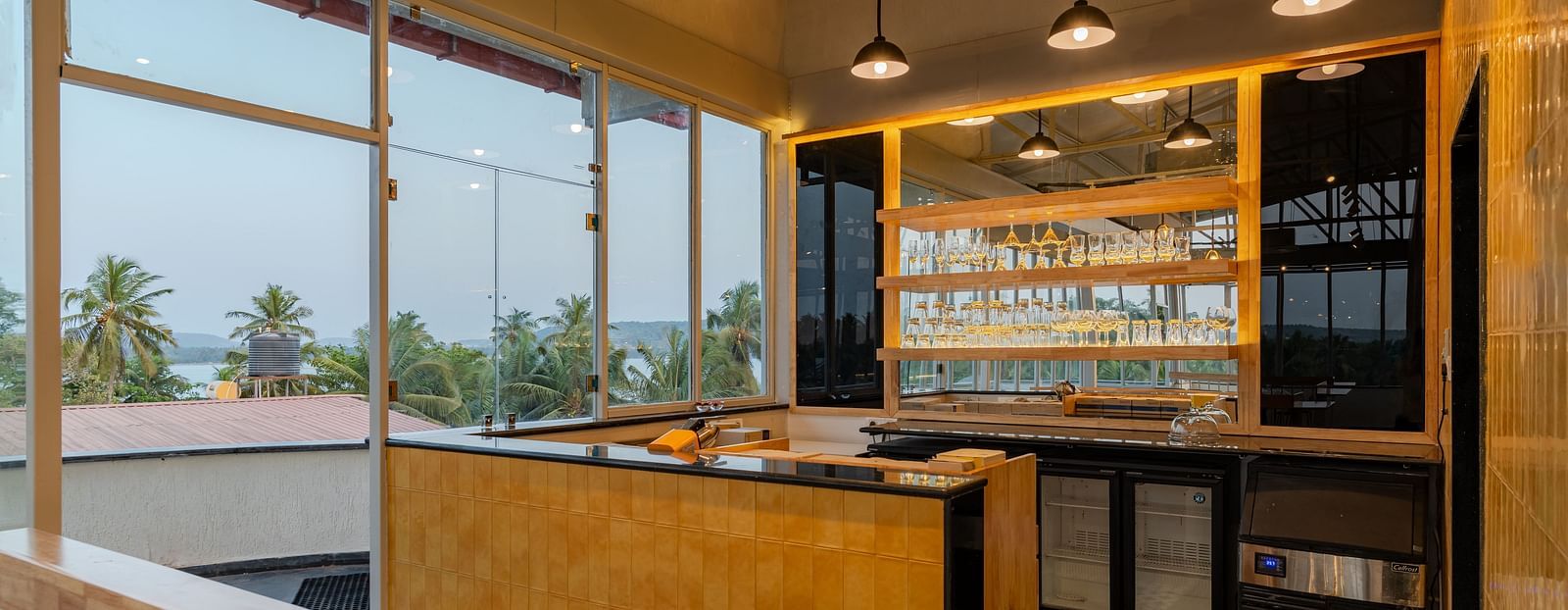 Interior of a contemporary cafe with bar stools and a window view. at Bedzzz Xclusiv Morjim, Goa
