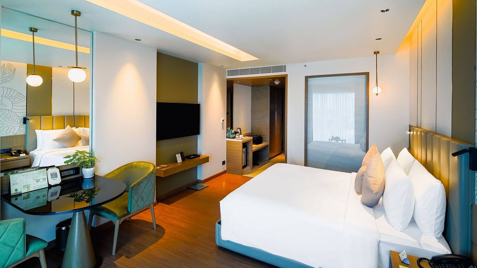 A room with a large bed, work desk, and a wall-mounted television - Grand Madurai by GRT Hotels