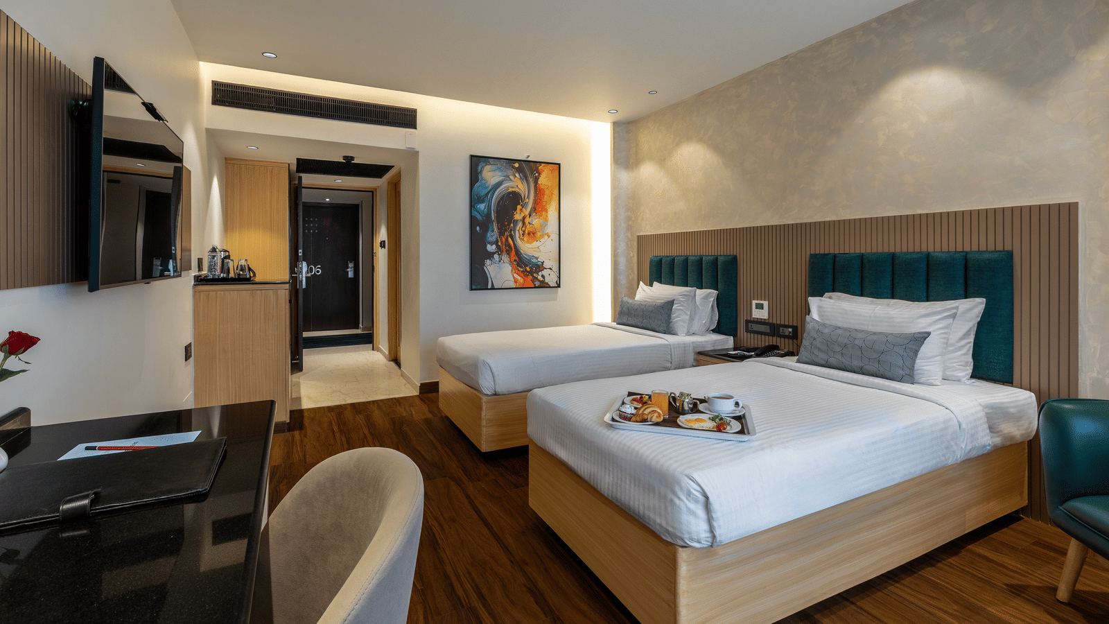 A well-lit hotel room at the Citrine Hotel with twin beds, a TV, and a mirror.