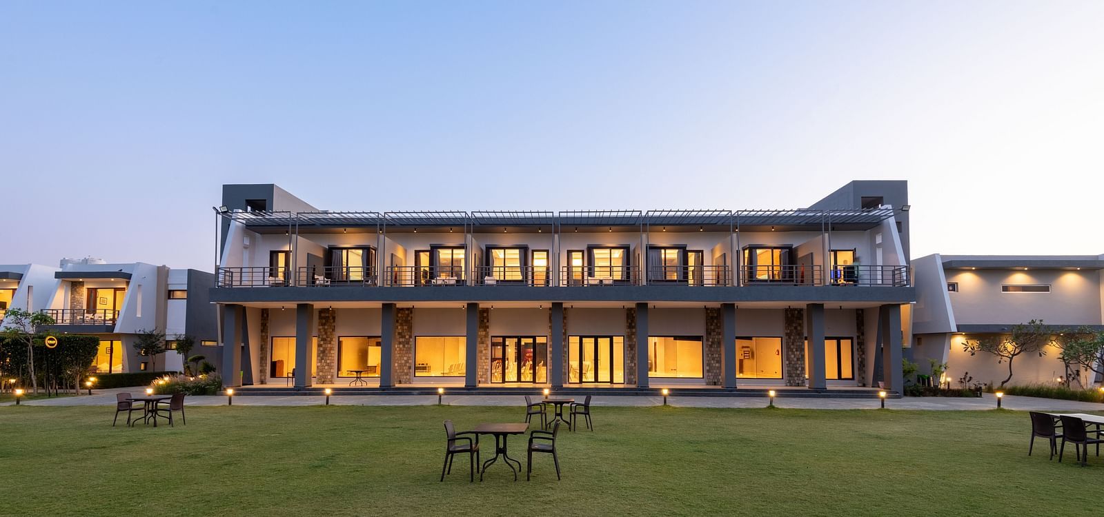 Facade view of DLS Forest Vines Resort, illuminated by warm lights from the windows and doors.