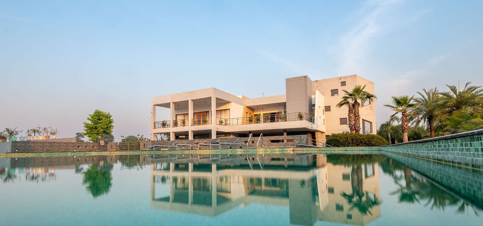 Facade view of DLS Forest Vines Resort with its reflection shimmering on the swimming pool under a clear sky.