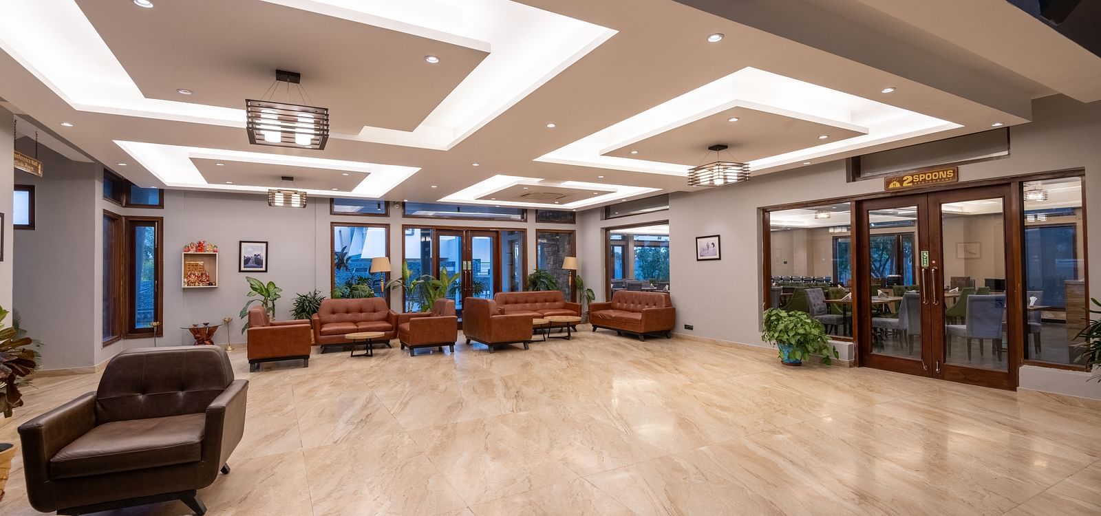 Reception area at DLS Forest Vines Resort, seen from the far end, featuring bright lighting and clean, cushioned sofas.