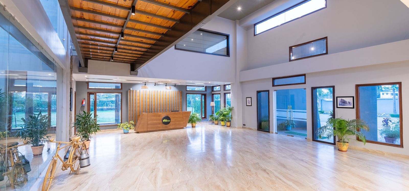 Reception desk at DLS Forest Vines Resort, located at the far end of the hall, featuring wooden ceiling interiors and bright lighting.
