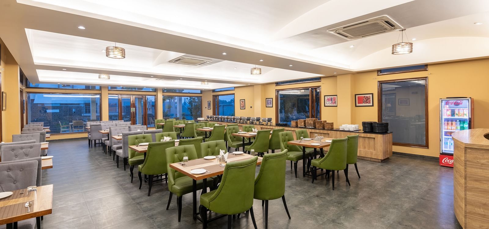 Brightly lit diagonal view of the restaurant at DLS Forest Vines Resort, showcasing tables and seating arranged for guests.