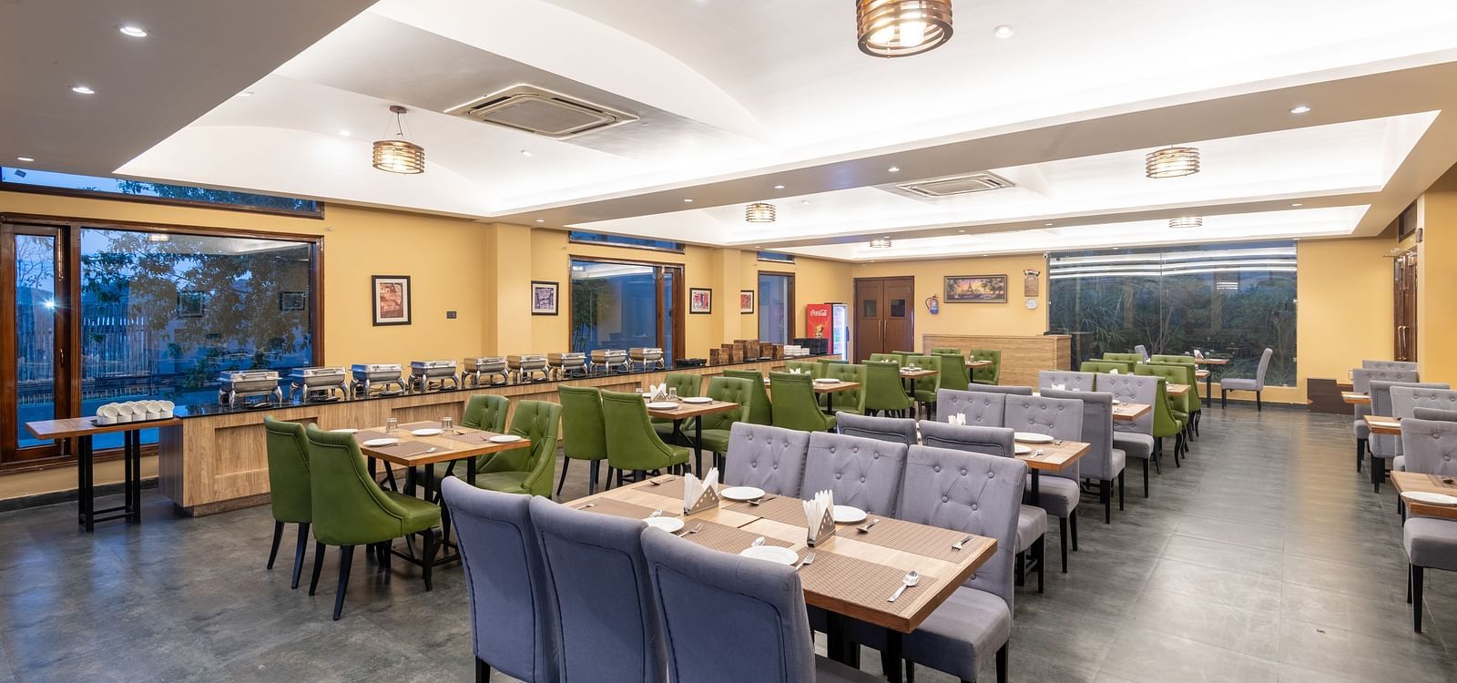 Diagonal view of the restaurant at DLS Forest Vines Resort, featuring tables and seating set for guests.
