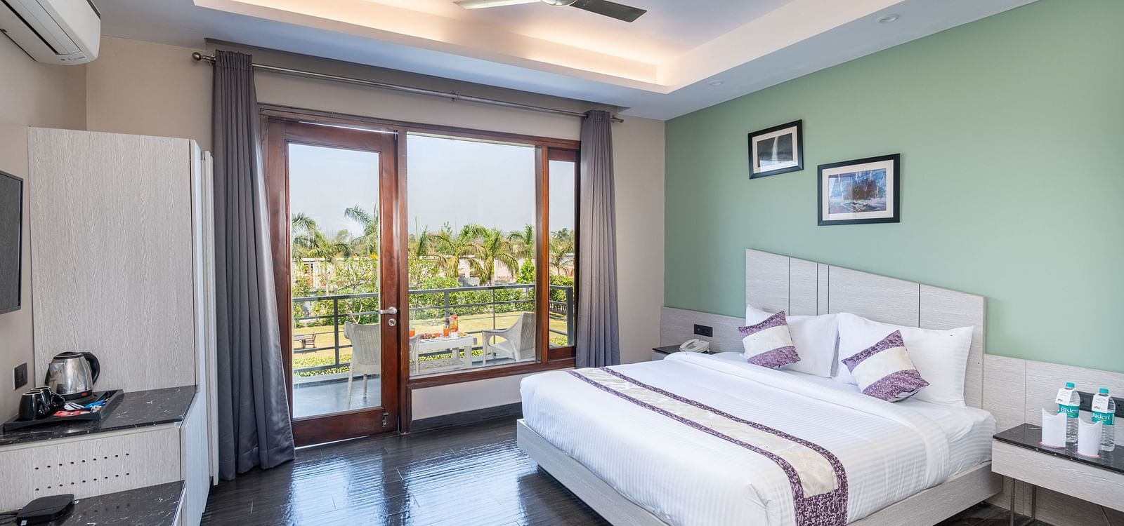 Spacious room at DLS Forest Vines Resort featuring a large bed, a bedside table, and a large glass door leading to the balcony.