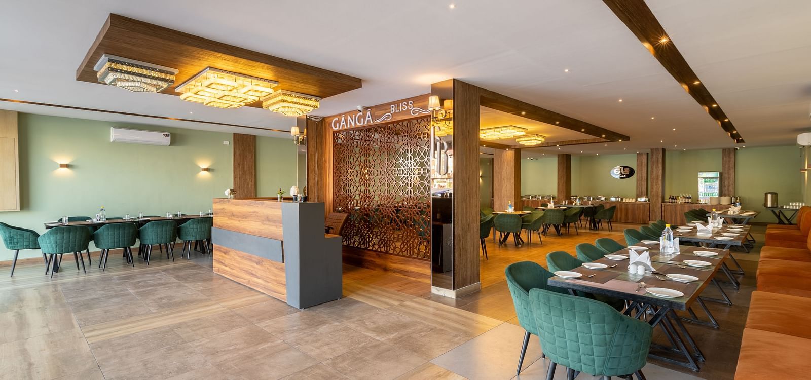 The restaurant image shot from a different angle of DLS Ganga Bliss, Haridwar with chairs, tables and warm lighting