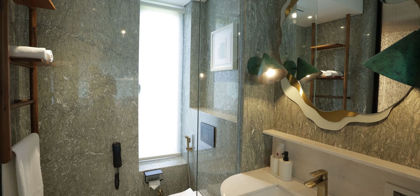 Elegant bathroom interior at Regency Hotel, Mumbai showcasing marble walls, modern fixtures, artistic lighting and premium toiletries for guest comfort.