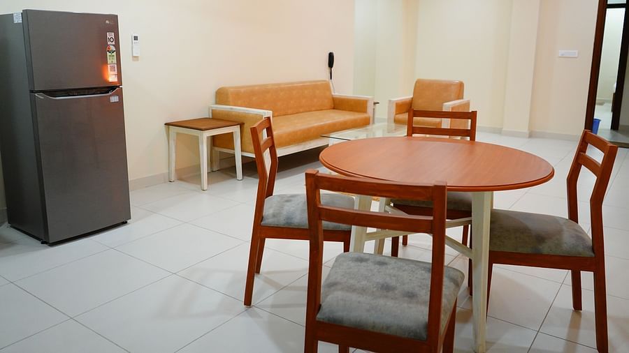A seating area featuring a fridge, a sofa set, a dining table and chairs - A M Suites