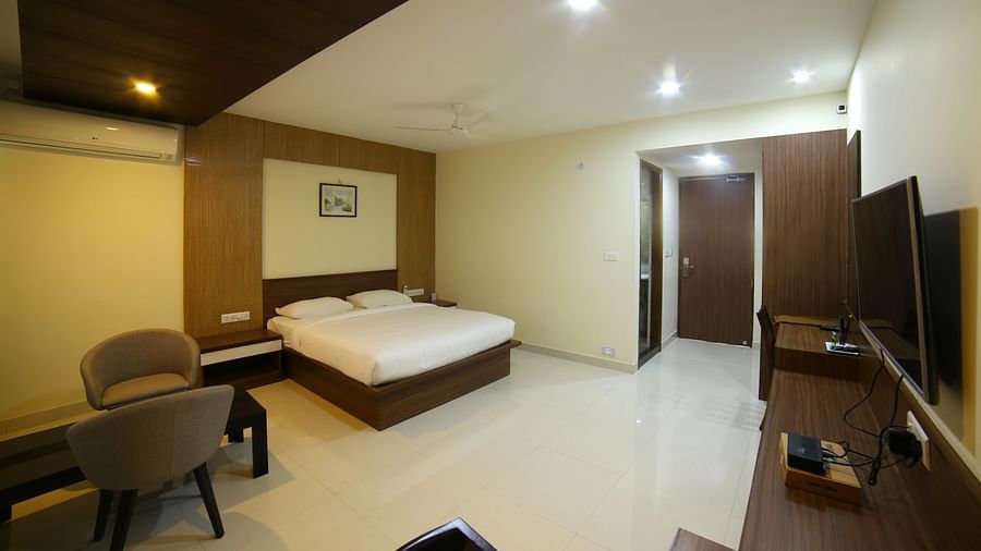 Mysore Gate Hotel, Bangalore Bengaluru A room featuring a well made bed sofa chairs a TV and a wall painting - Mysore Gate Hotel Bangalore