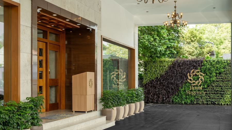 Hotel Royal Regency Chennai entrance with glass doors, greenery, and chandelier