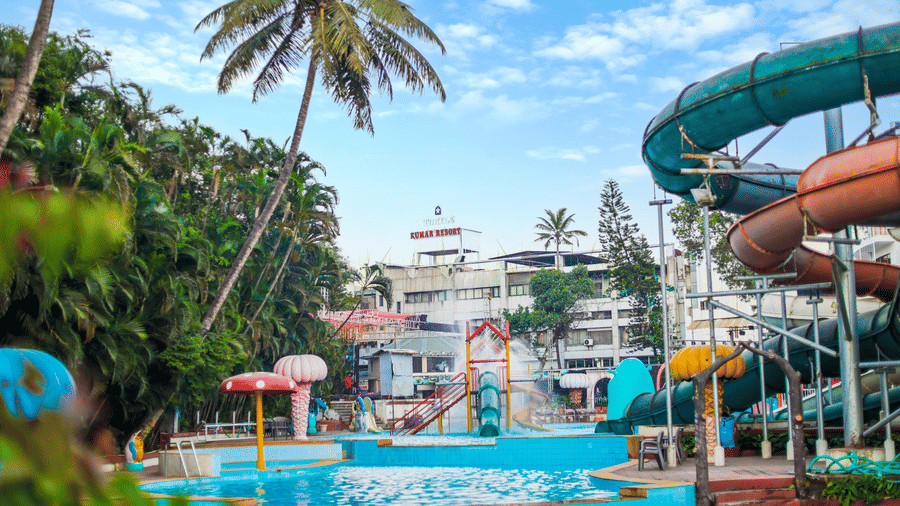 Tropical water park scene featuring palm trees, a large closed-loop water slide, and views of the surrounding resort amenities at Kumar Resort by Turtle.