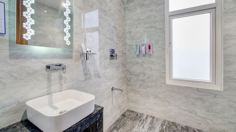 Spacious bathroom at Monday Hotels Amalapuram Heights with shower area, basin, and a mirror.