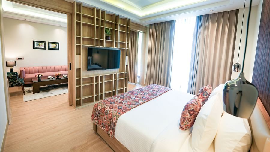 An image showcasing a bedroom of a suite in Kangra in the foreground, with the living area visible in the background - NAMAMI BY ZENQ BANKHANDI