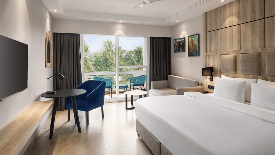 Standard room with a king size bed, work desk and balcony overlooking the pool.